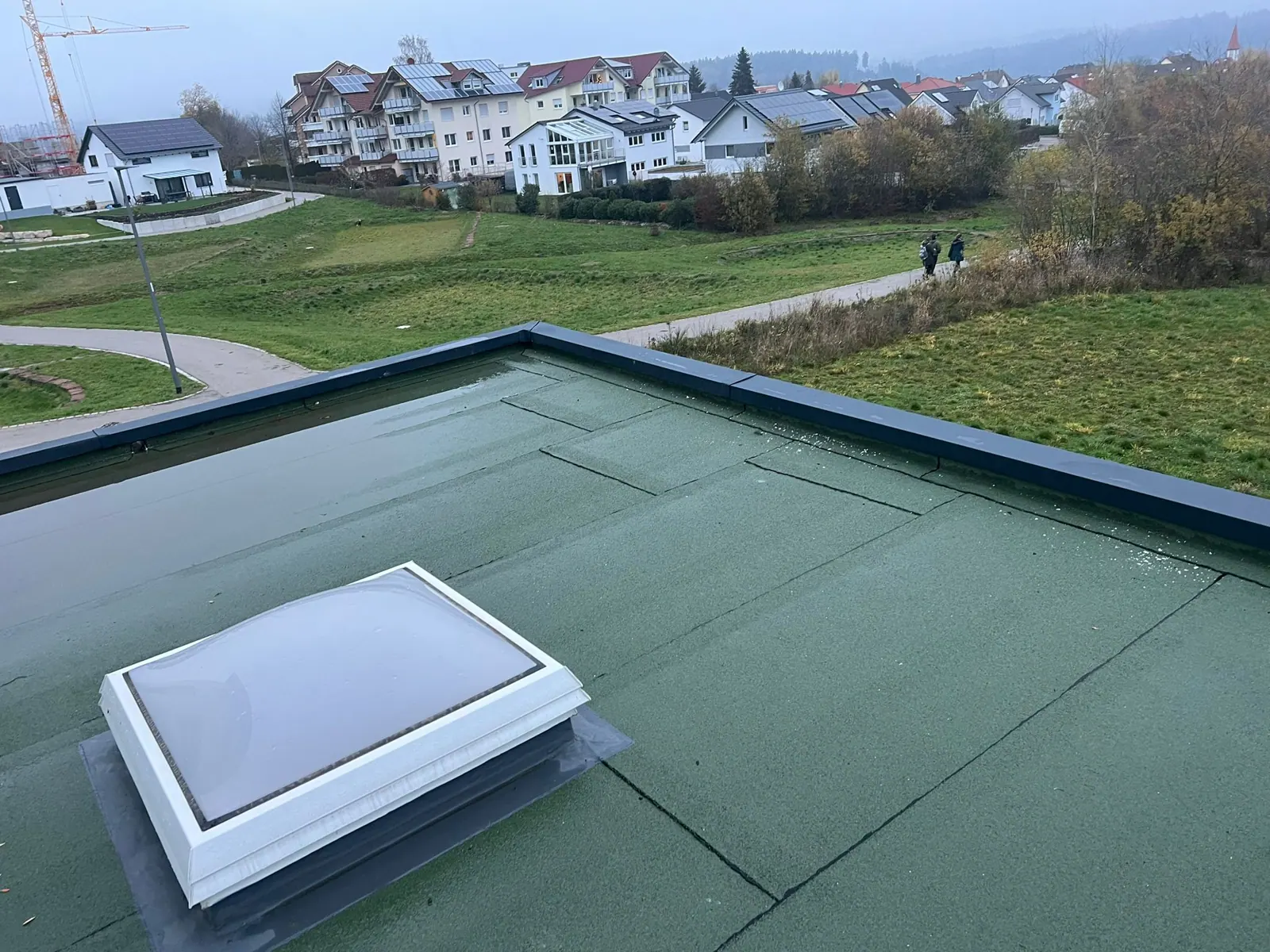 Flachdach mit grüner Bitumenbahn und Lichtkuppel